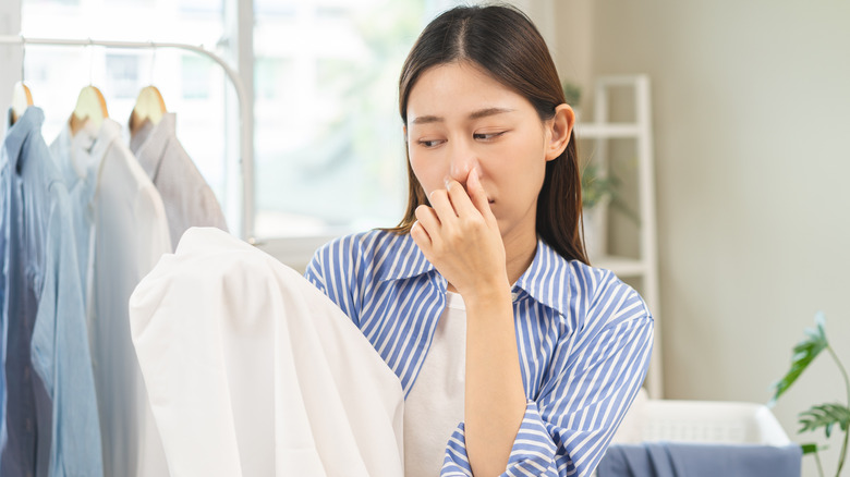 person covering nose holding laundry