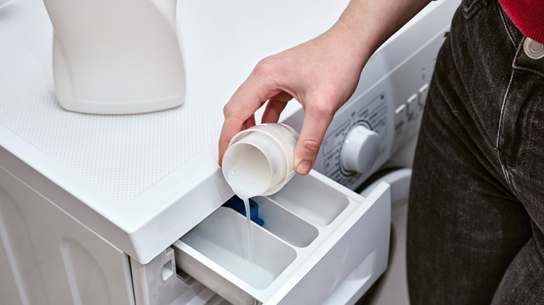 person pouring detergent into washer