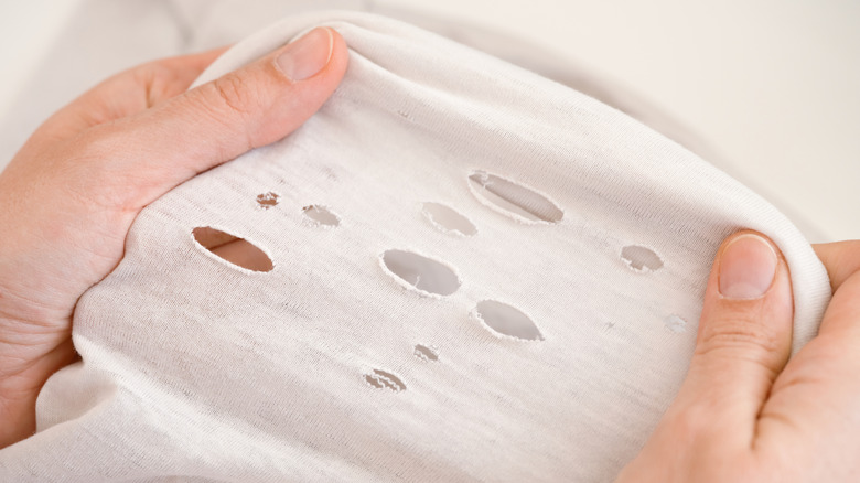 hands holding ripped fabric