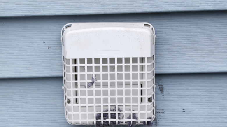 An outdoor vent shows discolored marks on nearby siding