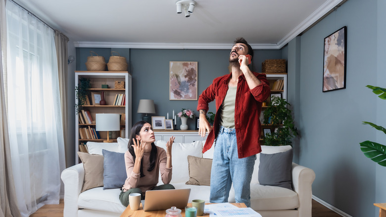 A couple looks nervous about noises heard upstairs in their house