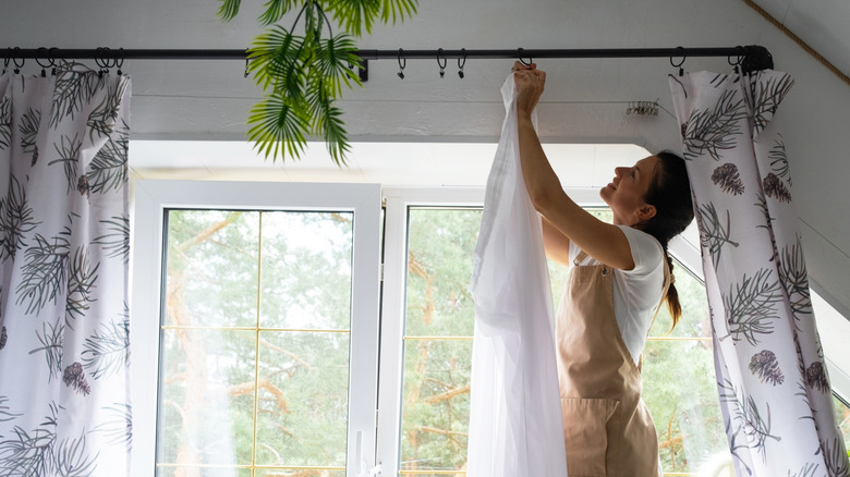 Woman uses curtain clips to hang DIY curtains.