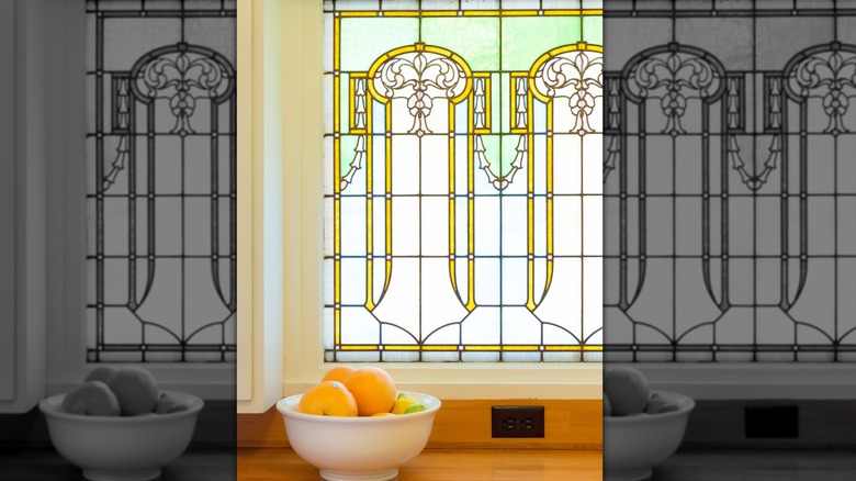Stained glass window in a kitchen behind a bowl of oranges.