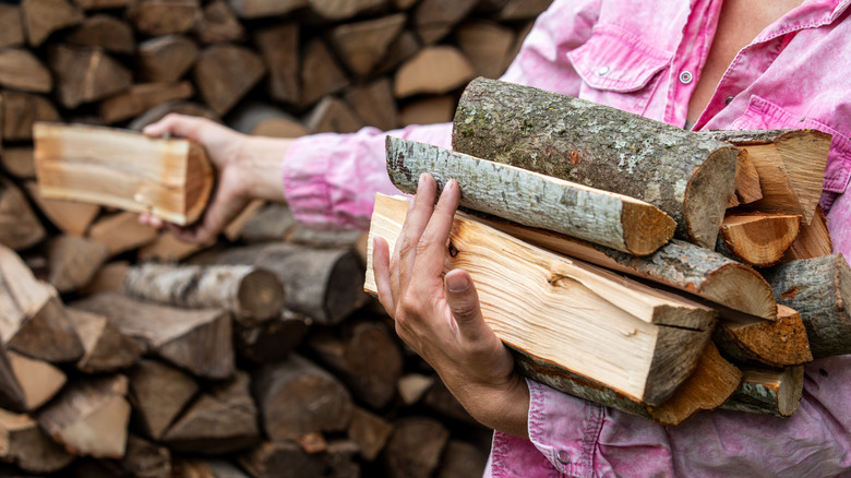 Close up of a woman picking and carrying logs outside