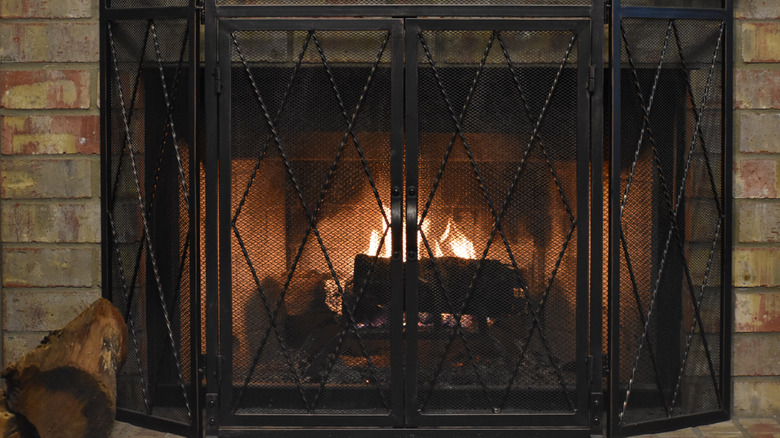 Black iron fireplace screen in front of a brick fireplace