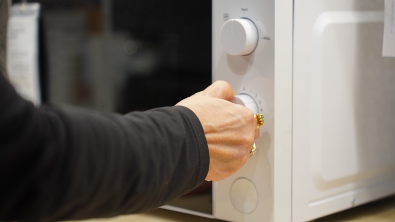 older woman setting microwave timer