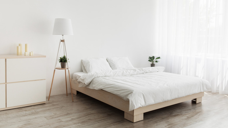 Bedroom with neutral-colored bed and decor beside a large window