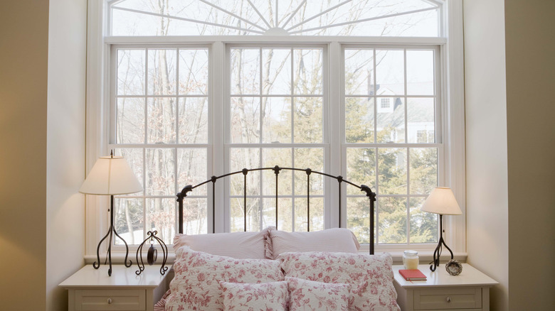 Wrought-iron bed in front of paned windows