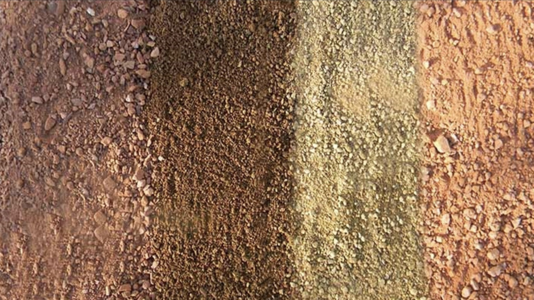 Four stripes of pink, brown, yellow, and tan decomposed granite
