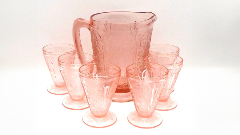 A set of vintage Jeannette Pink Cherry Blossom Depression glass tumblers surround a matching pitcher