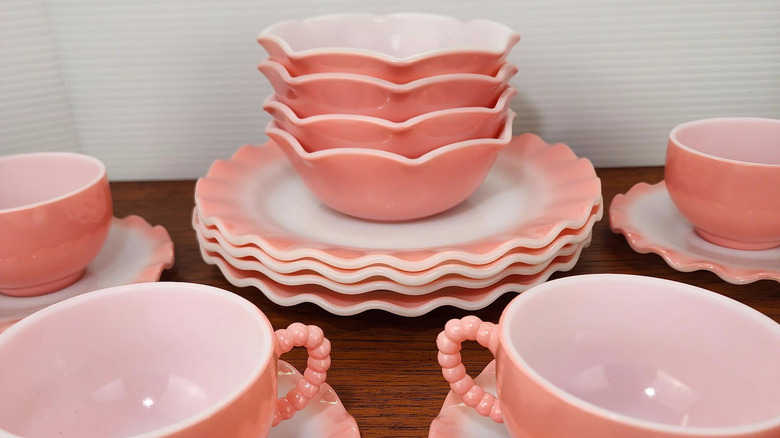 A beautiful set of Hazel Atlas Pink Crinoline rippleware cups, saucers, and bowls sits on a wooden table