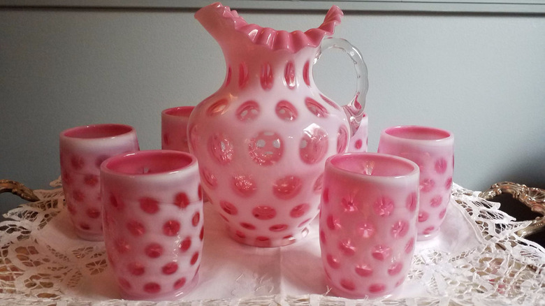 A set of Fenton Cranberry Opalescent Coin Dot glassware sits on a white doily-topped silver tray