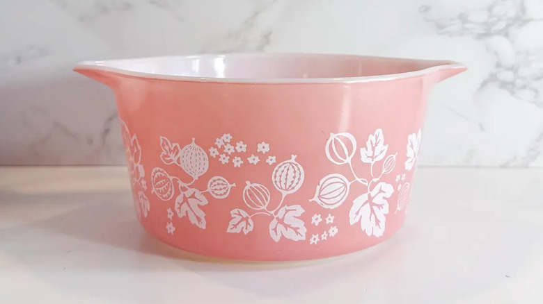 A vintage Pink Gooseberry Pyrex casserole dish sits on a white counter