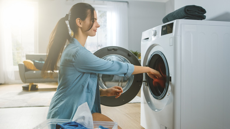 Woman sitting on the floor remocing clothes from a dryer