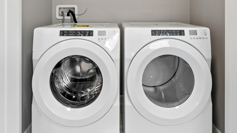 A dryer and a washing machine next to each other in a small laundry closet