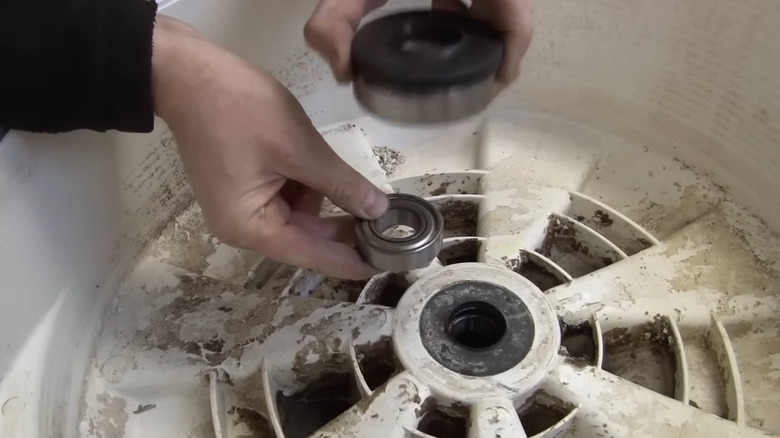 Man's hand holding drum bearings of a dryer