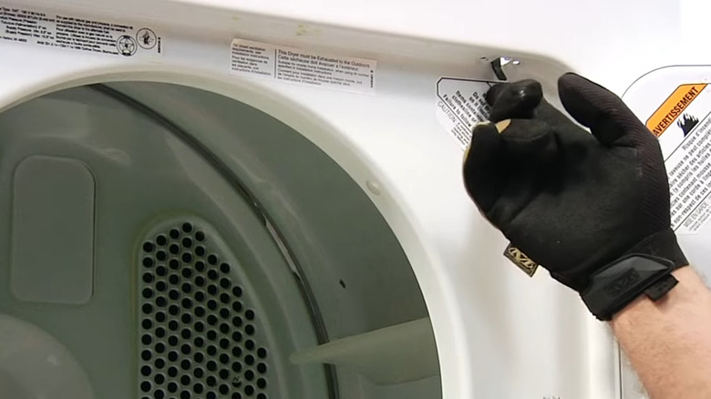 Man with gloves touching the door switch of a dryer