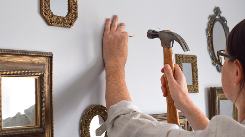 Closeup of woman hammering and hanging stuff for gallery wall