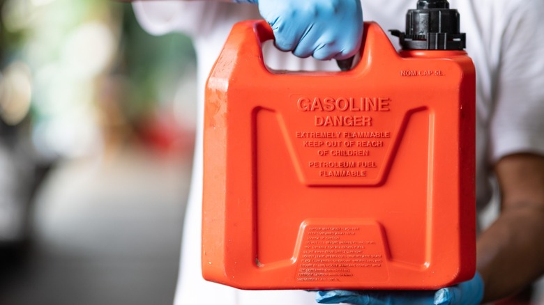 Person holding up a red container of gasoline