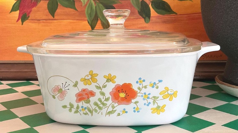 Vintage CorningWare Wildflower casserole dish with a lid on a green checkered surface