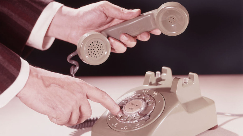Vintage rotary phone with man holding the receiver and dialing