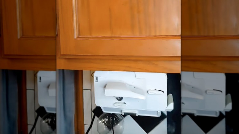 Screen shot of TikTok demonstrating a black and decker spacemaker can opener underneath a cabinet.