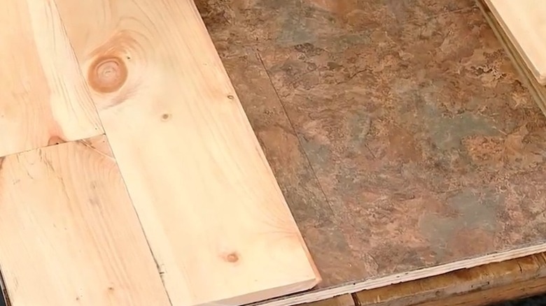 Pine planks are nailed to linoleum floors.
