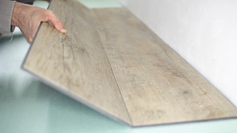 Hands shown locking in luxury vinyl tiles.