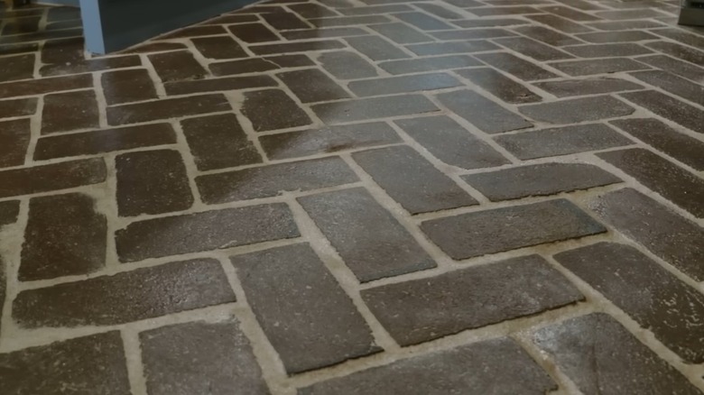 Brown reclaimed brick laid as flooring in a herringbone pattern.