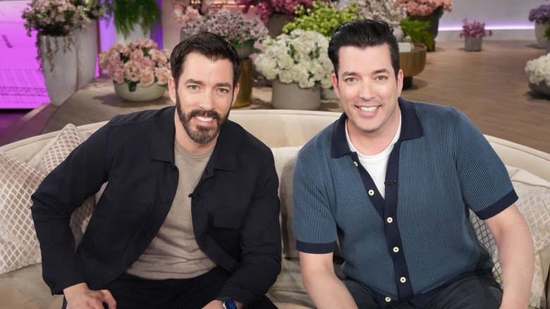 Property brothers Drew and Jonathan Scott smiling on a couch