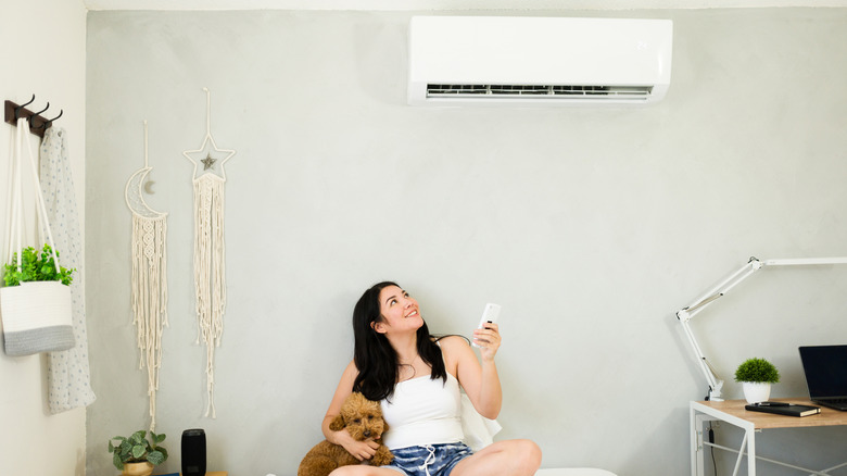 A smiling woman is turning on the AC in her home