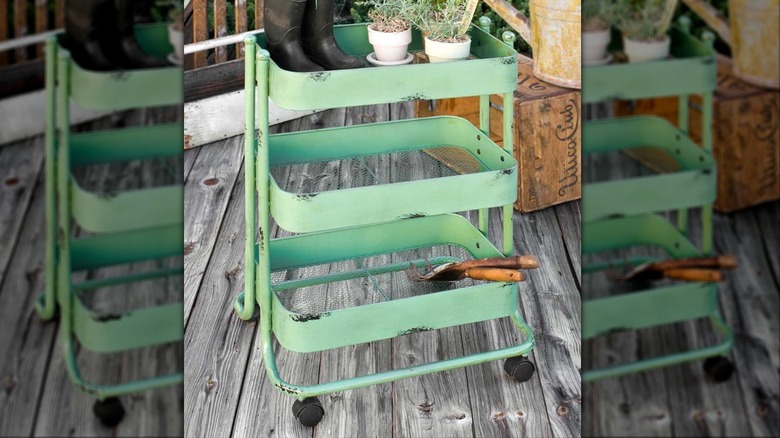 Green enamel garden cart with garden tools on it