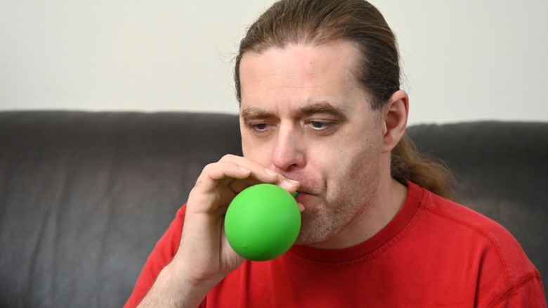 Man blowing up green balloon