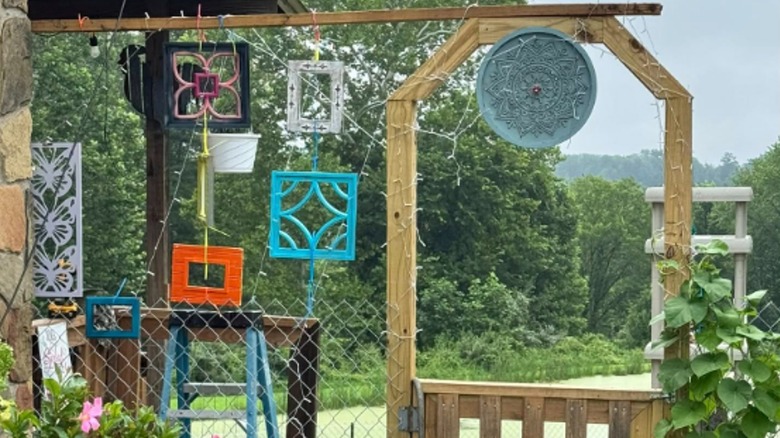 A collection of empty photo frames hang in a garden.
