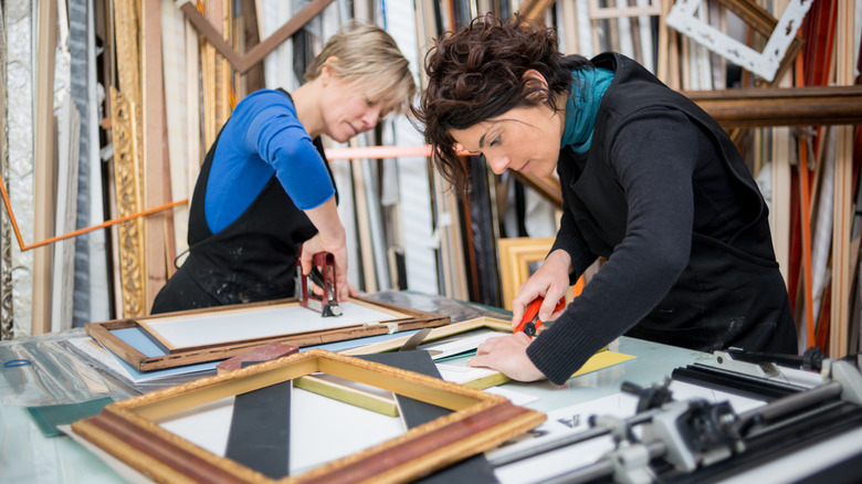 Two people in a frame shop building picture frames