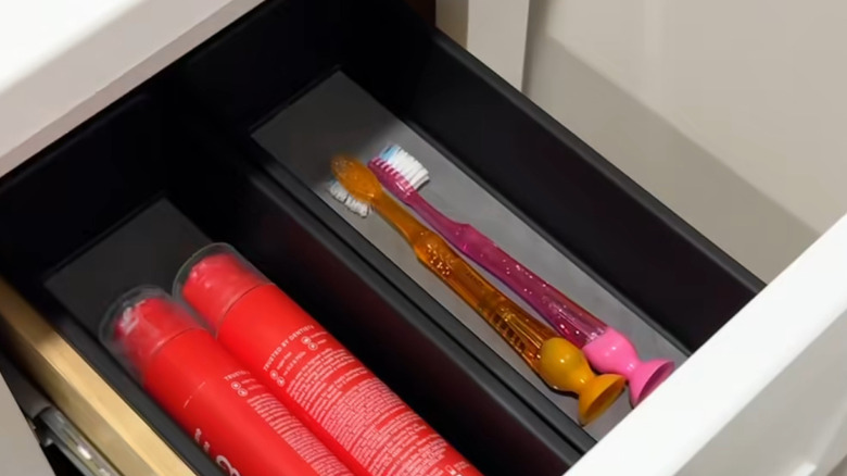 Two of the medium length drawer organizers side-by-side with health and beauty products in them