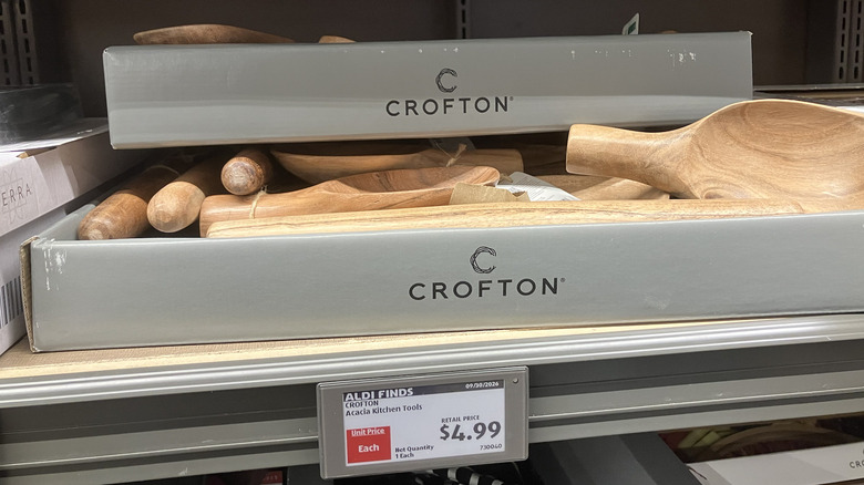 A Crofton-branded box full of acacia wood kitchen tools on an Aldi store shelf.