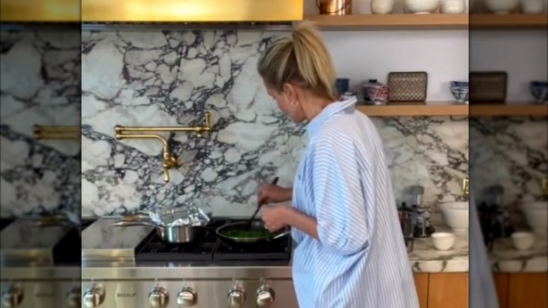 Cameron Diaz cooking in her kitchen with marble veined backsplash