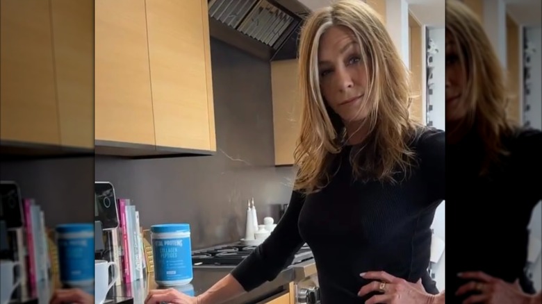 Jennifer Aniston in her modern kitchen with black slab backsplash