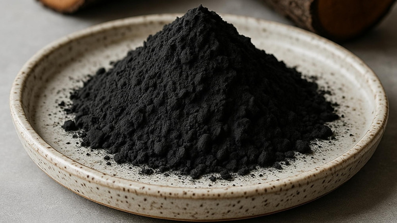 A small pile of activated charcoal powder in a ceramic dish.