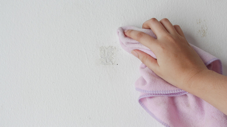 Hand wiping sticker residue off of wall