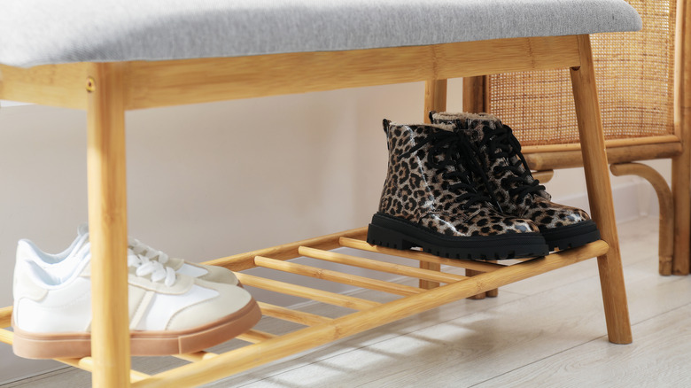 Close up of boots and shoes stored on bottom shelf of bench