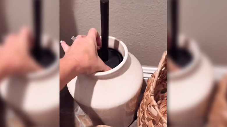 Toilet brush concealed in a white vase next to a woven basket