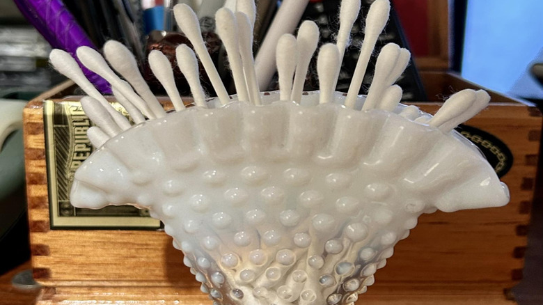 White glass Fenton vase holding Q-tips