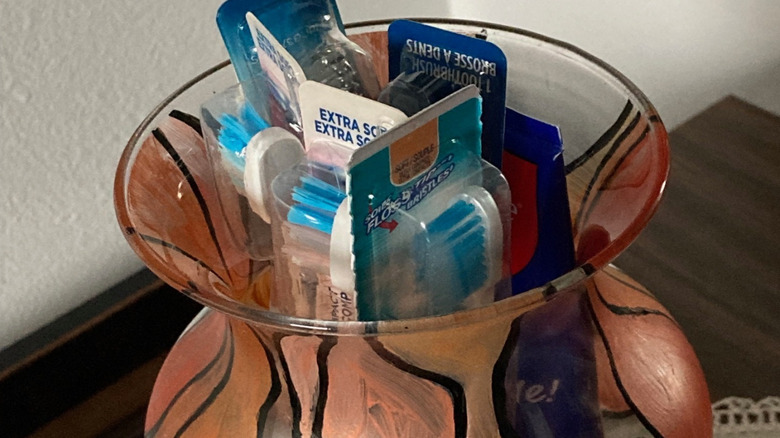 Orange and black patterned glass vase stuffed with new toothbrushes