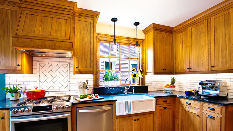 Honey oak cabinets in kitchen with black hardware and countertops