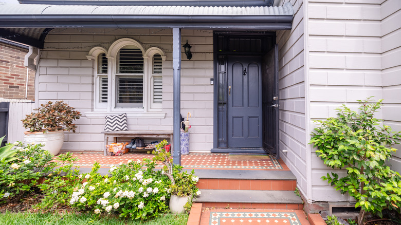 Slate blue front door on home with terra cotta tile porch