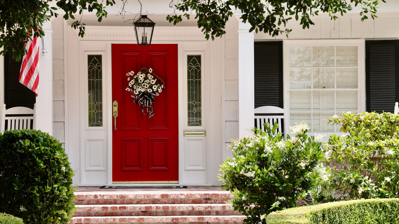 White house with red front door and large windows with black shutters