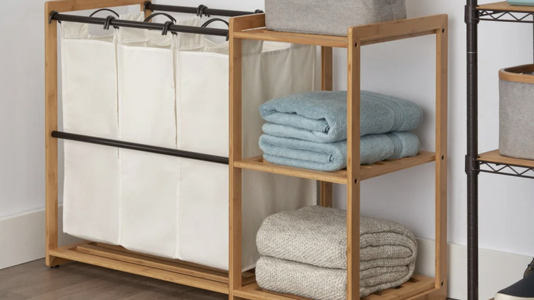 Bamboo laundry rack with storage bags and folded towels sitting on the bamboo shelves