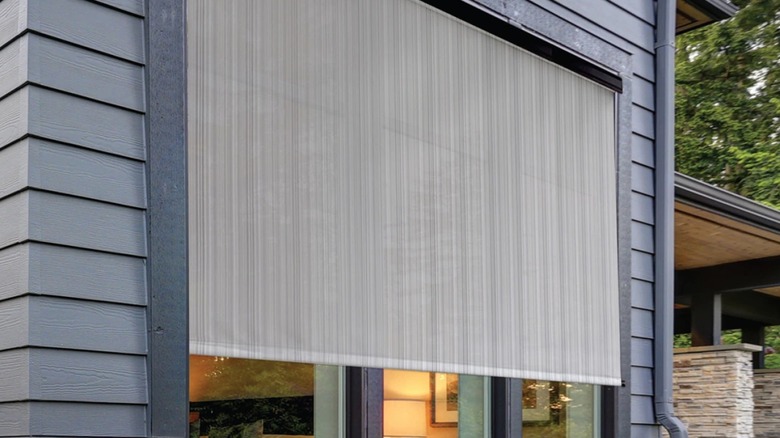 Koolspot sun shade over a window on a gray/blue house